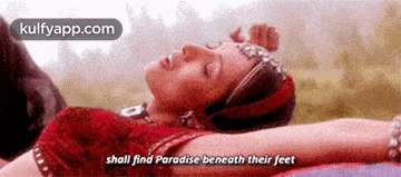 a woman is laying on a blanket with her eyes closed and says `` shall find paradise beneath their feet ''
