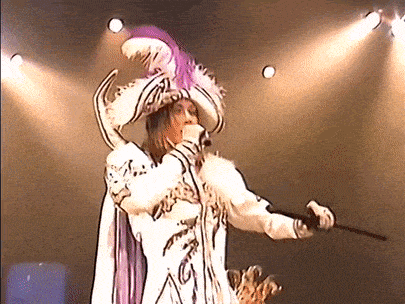 a man in a costume is singing into a microphone while holding a cane