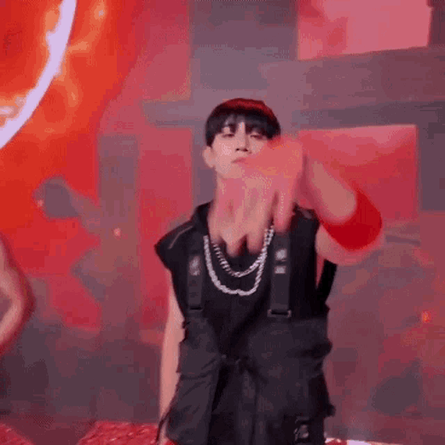 a man in a black vest is dancing on a stage with a red background .