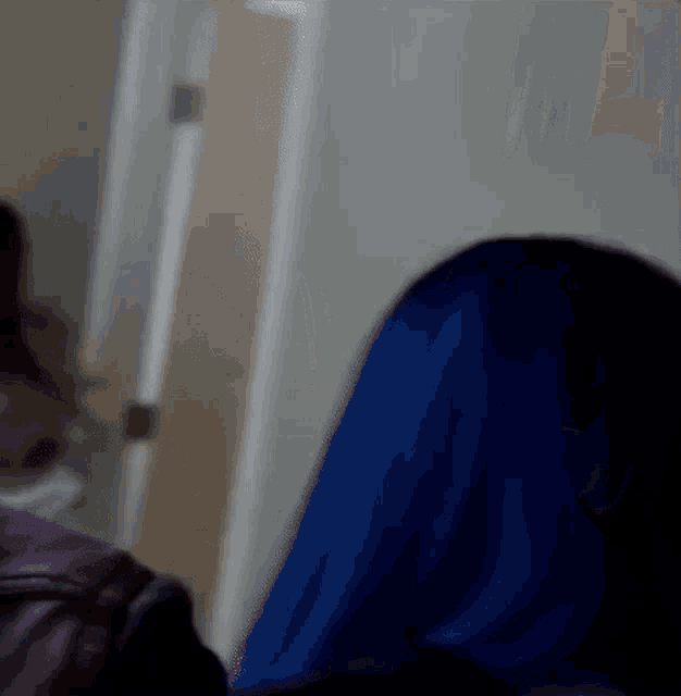 a woman with blue hair is standing in a room next to another woman .
