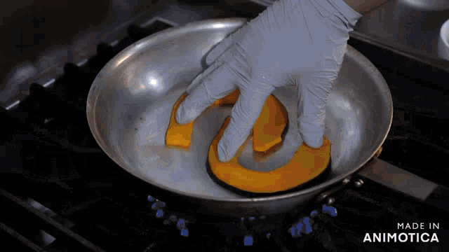 a person is cooking a pumpkin in a frying pan with the words made in animotica below it