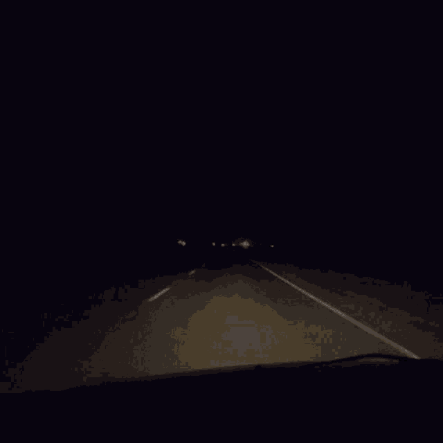 a car is driving down a highway at night in the dark