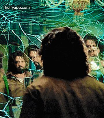 a man is standing in front of a broken mirror with a group of people behind him .