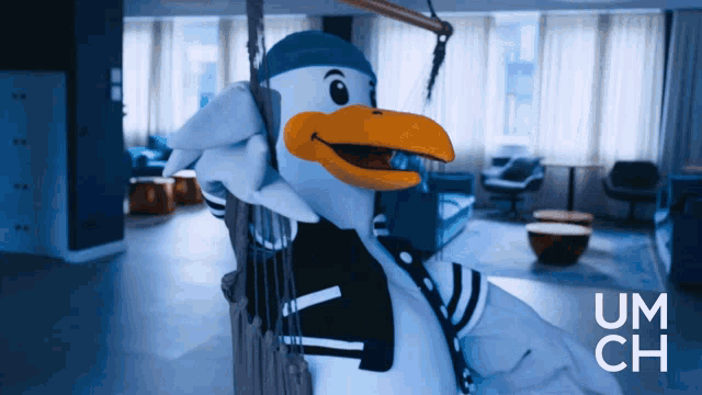 a seagull mascot is hanging on a rope swing in a room with um ch written in the corner