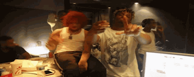 a man with red hair is giving the middle finger while sitting next to another man