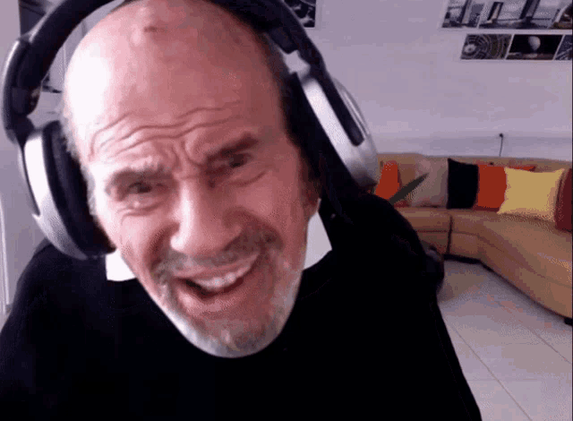 a bald man with a beard wearing headphones and smiling