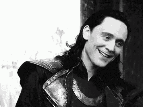 a black and white photo of a man with long hair and a sword smiling .