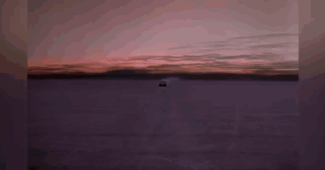 a car is driving down a road with a sunset in the background ..