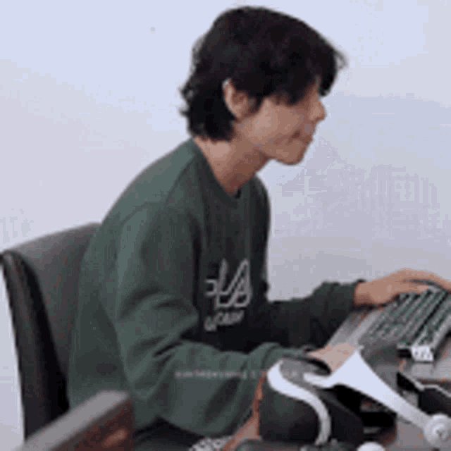 a man in a green sweater is typing on a computer keyboard