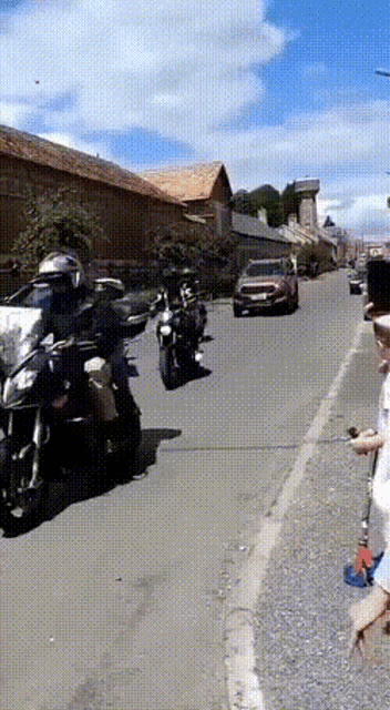 a group of motorcycle riders are riding down a street