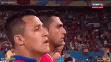 a group of men are standing next to each other on a soccer field watching a game .