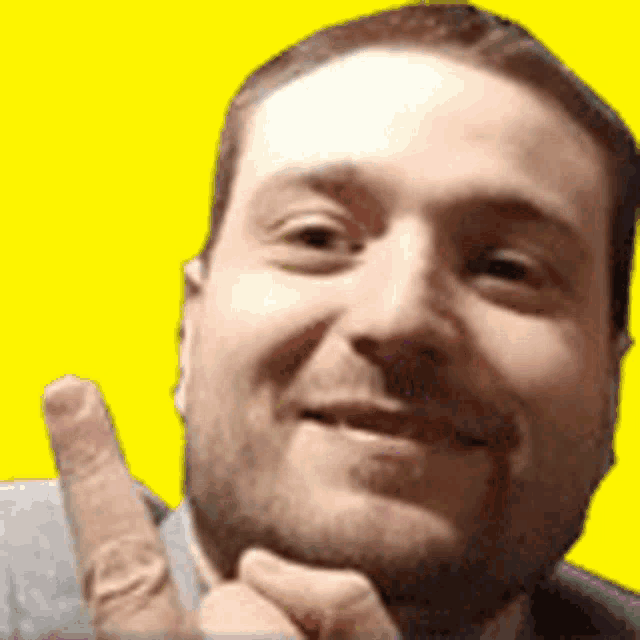 a man with a beard is smiling and giving a middle finger