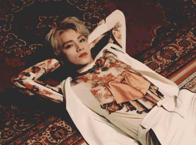 a man in a floral shirt is laying on a rug