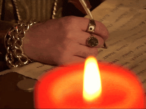 a person with a ring on their finger writes on a piece of paper