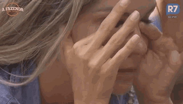 a close up of a woman covering her face with her hands .