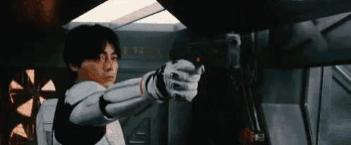 a man in a futuristic costume is pointing a gun at someone .