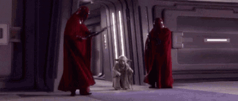 a group of people in red robes are standing next to a statue of yoda .