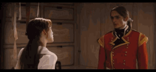 a woman in a white shirt is standing next to a man in a red coat .