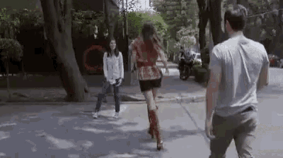 a man and a woman are walking down the street .