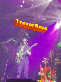 a man playing a guitar in front of a sign that says trevor bass on it