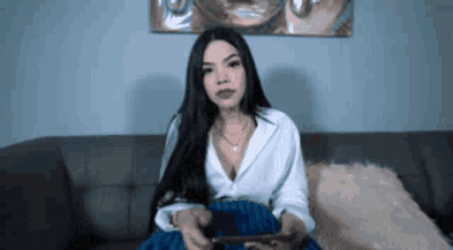 a woman is sitting on a couch holding a nintendo switch .