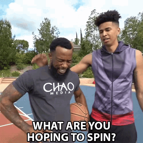 a man wearing a chaos media shirt stands next to another man holding a basketball