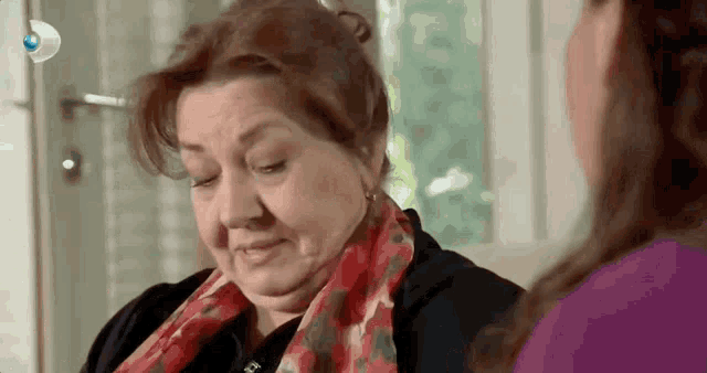 a woman with a scarf around her neck is crying while talking to another woman .