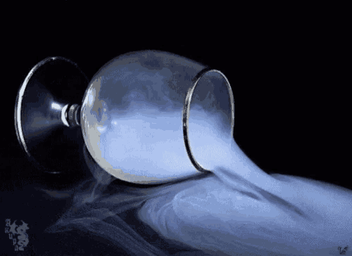 a wine glass with smoke coming out of it on a black background .