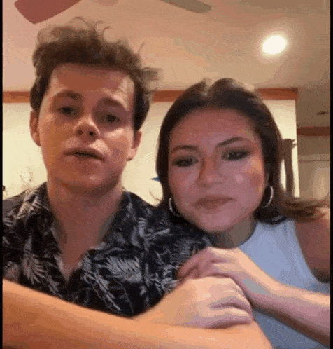 a man and a woman are sitting next to each other in a room with a ceiling fan .