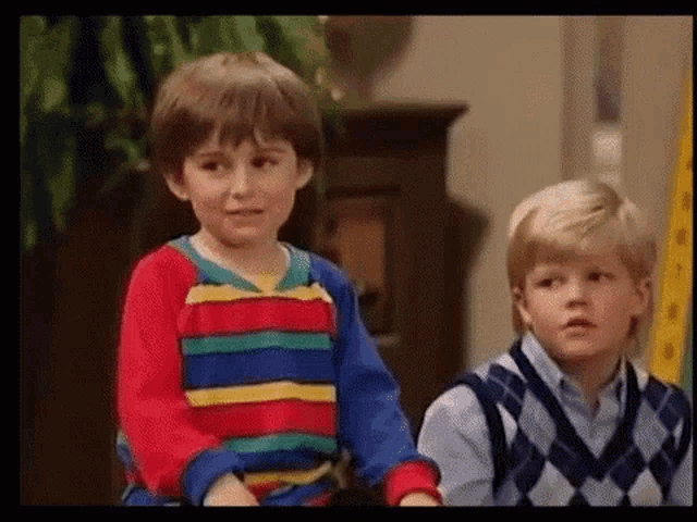 two young boys are standing next to each other in a room .