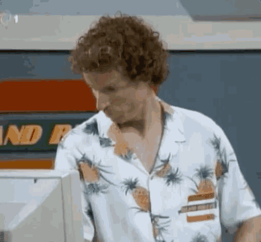 a man in a pineapple shirt is standing in front of a computer screen .
