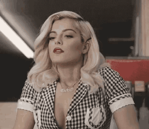 a woman wearing a plaid shirt and a necklace is sitting at a table in a diner .