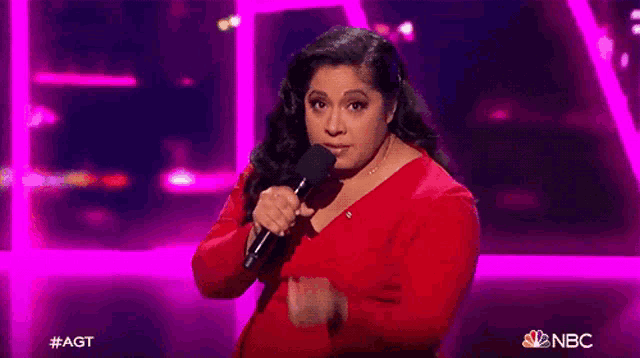 a woman in a red dress is singing into a microphone