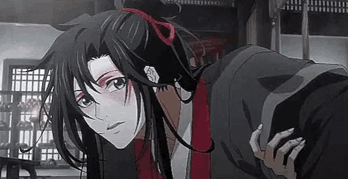 a close up of a person with long hair and a red ribbon in their hair standing in a room .
