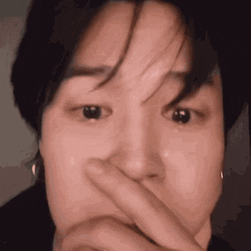a close up of a person covering their face with their hand .