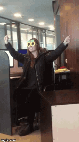 a woman wearing sunglasses is sitting in a cubicle in front of a computer