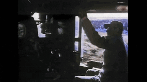 a man in a hat is driving a train .