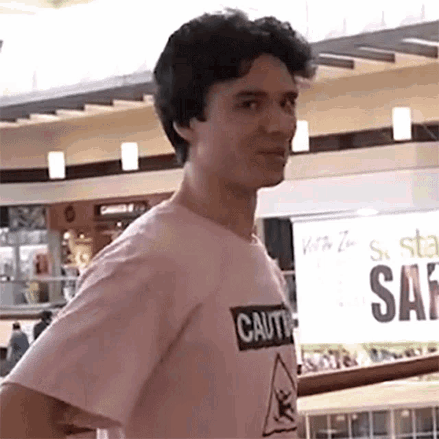 a young man wearing a pink shirt that says caution