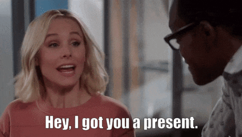 a woman is talking to a man in an office and saying hey , i got you a present .