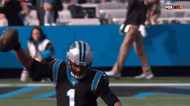 a man in a carolina panthers uniform is throwing a football .