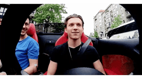 a man is sitting in the driver 's seat of a car with another man .