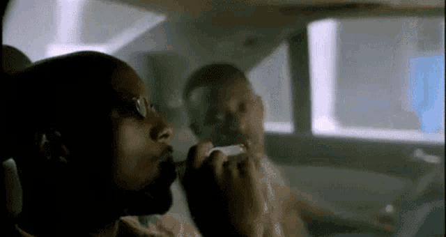 two men are sitting in the back seat of a car smoking cigarettes .
