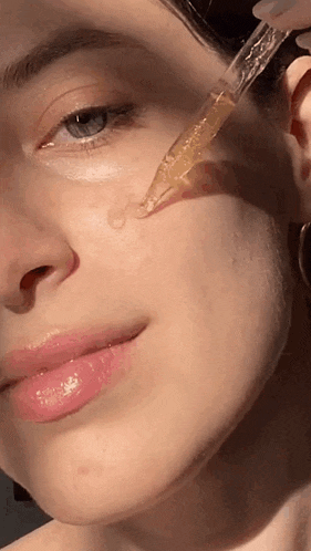 a woman is applying a serum to her face .