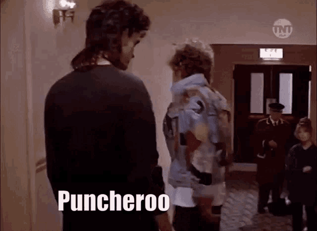 two men are standing in a hallway and the word puncheroo is on the bottom