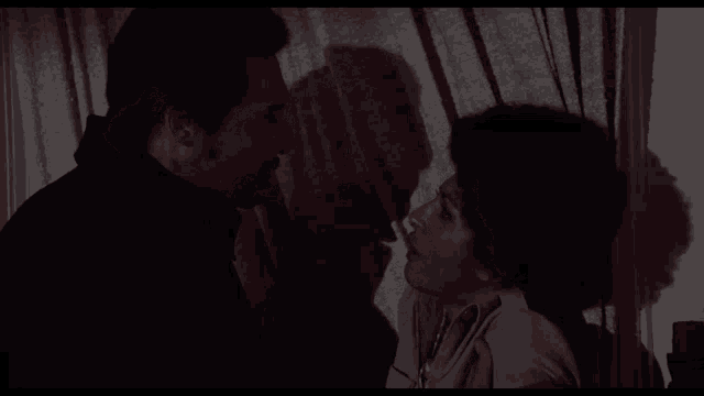 a man and a woman are standing in front of a window .