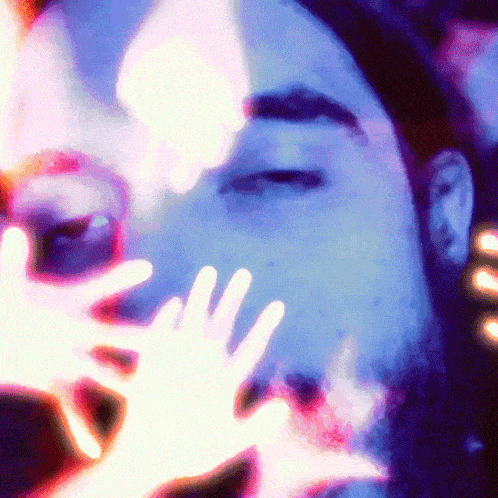 a close up of a man 's face with his eyes closed and glowing hands behind him