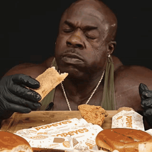 a man eating a sandwich from a popeye 's bag