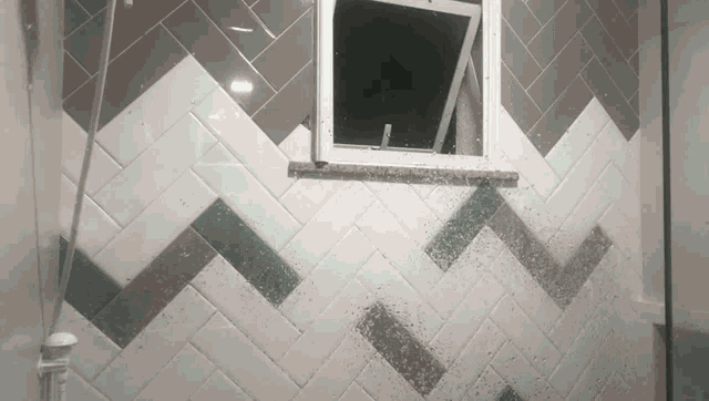 a broken window in a bathroom with a herringbone pattern on the wall