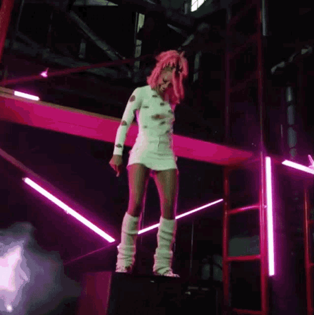 a woman in a pink wig is standing on a scaffolding