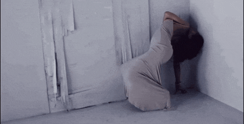 a woman in a long dress is kneeling in a corner
